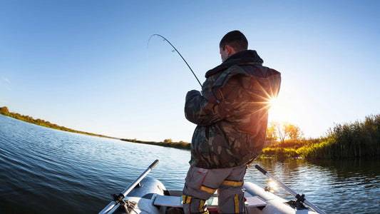Man fishing in a boat at sunset