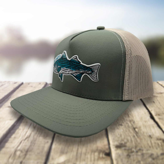 Angled view of the Six Knots Trophy Season Snapback Hat on a dock with a blurred marina background, highlighting the breathable mesh back — premium water-resistant fishing hat in green and tan featuring a bold embroidered striped bass patch and Six Knots logo. Built for durability, breathability, and all-day comfort—ideal for saltwater fishing, offshore boating, and rugged coastal lifestyle wear in any weather.