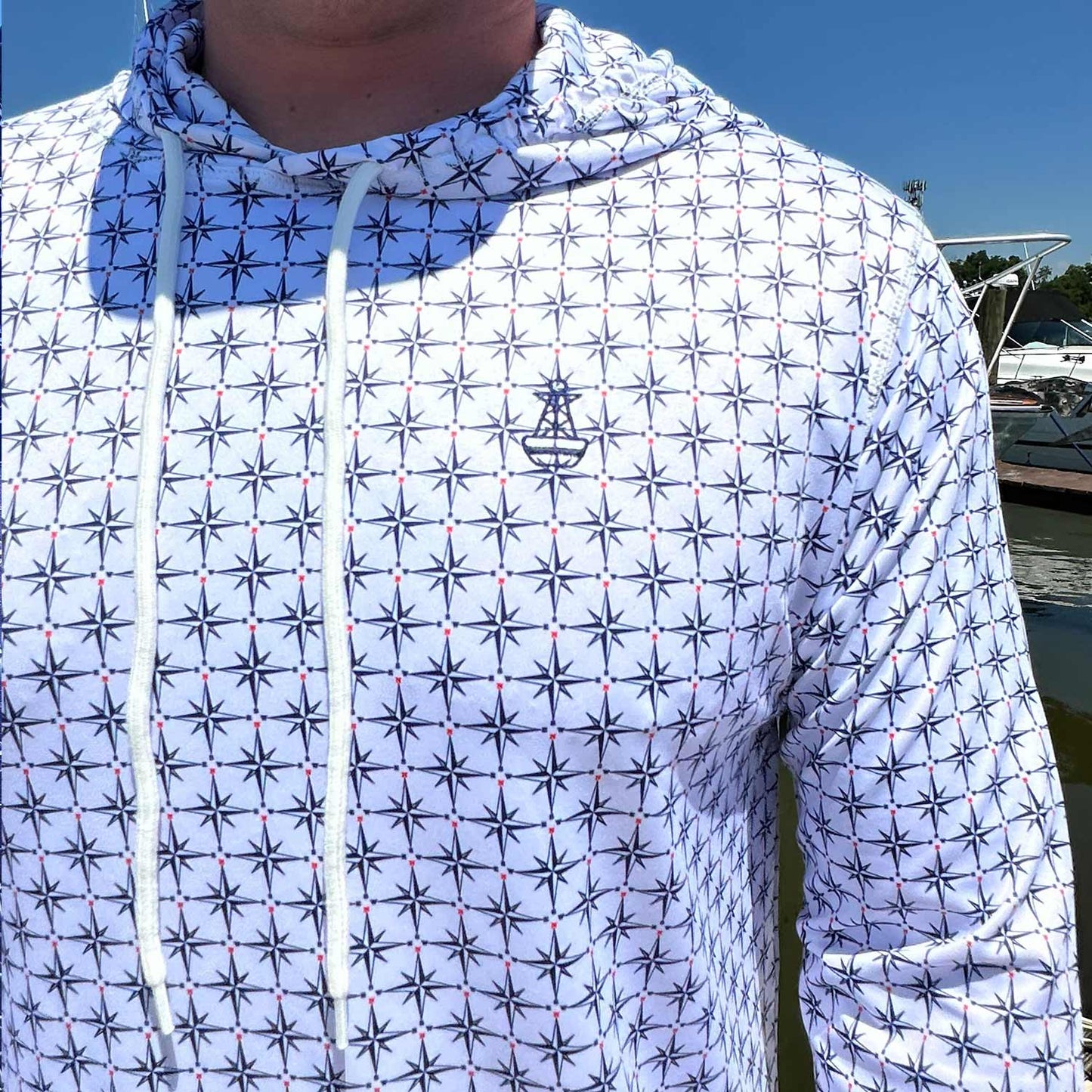 Close-up of the Six Knots True North Men's Performance Hoodie in white, highlighting the detailed compass pattern and signature Six Knots buoy logo. This lightweight, moisture-wicking hoodie features UPF sun protection and quick-dry performance—ideal for boating, saltwater fishing, and warm-weather coastal adventures.