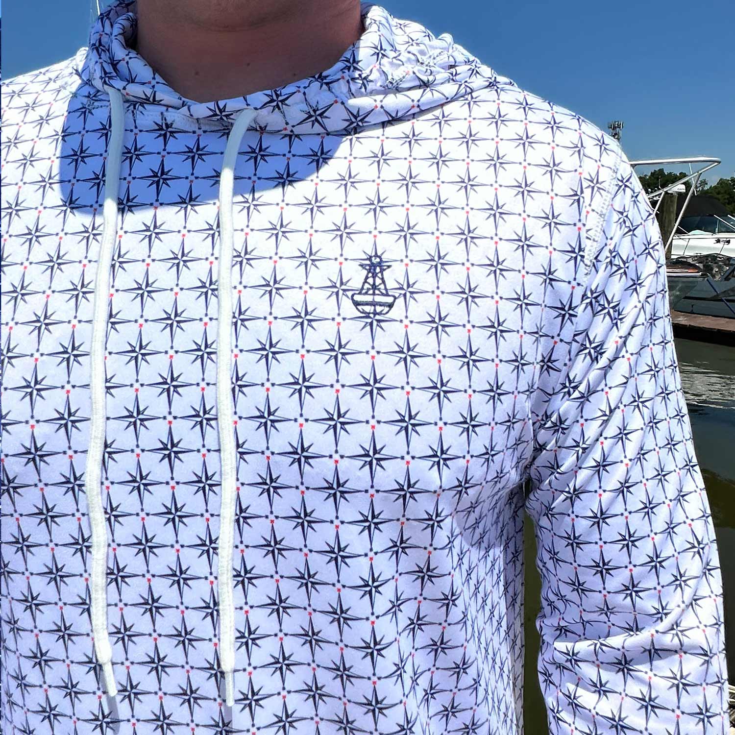 Close-up of the Six Knots True North Men's Performance Hoodie in white, highlighting the detailed compass pattern and signature Six Knots buoy logo. This lightweight, moisture-wicking hoodie features UPF sun protection and quick-dry performance—ideal for boating, saltwater fishing, and warm-weather coastal adventures.