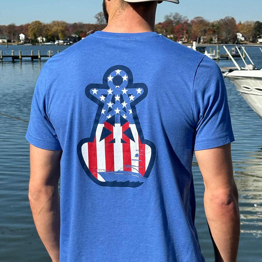 Rear view of a man at a Maryland marina wearing the blue Six Knots American Buoy Classic T-Shirt. This lightweight, ultra-soft unisex tee is crafted from a breathable cotton-polyester blend and showcases a bold buoy graphic featuring an American Flag pattern inside the iconic Six Knots buoy logo. Ideal for everyday wear, weekend relaxation, coastal vacations, casual outings, and effortless waterfront style.