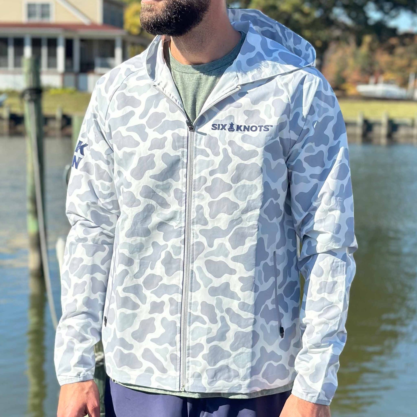 Man on a dock wearing Six Knots Coastal Camo Rain Jacket — waterproof, lightweight outerwear for fishing, boating, and coastal adventures