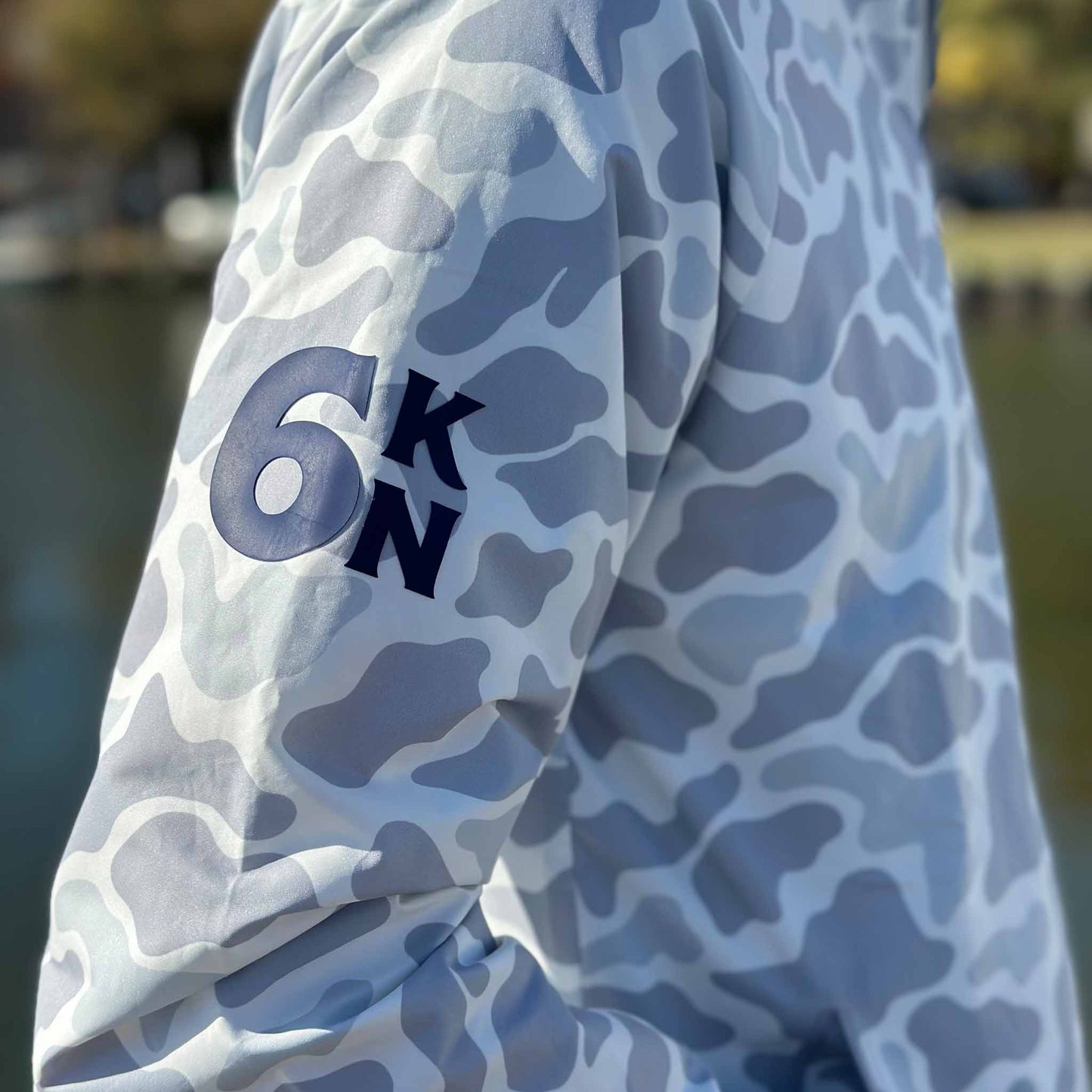 Close-up of Six Knots Coastal Camo Rain Jacket sleeve featuring the 6KN emblem — waterproof, lightweight outerwear for boaters and anglers