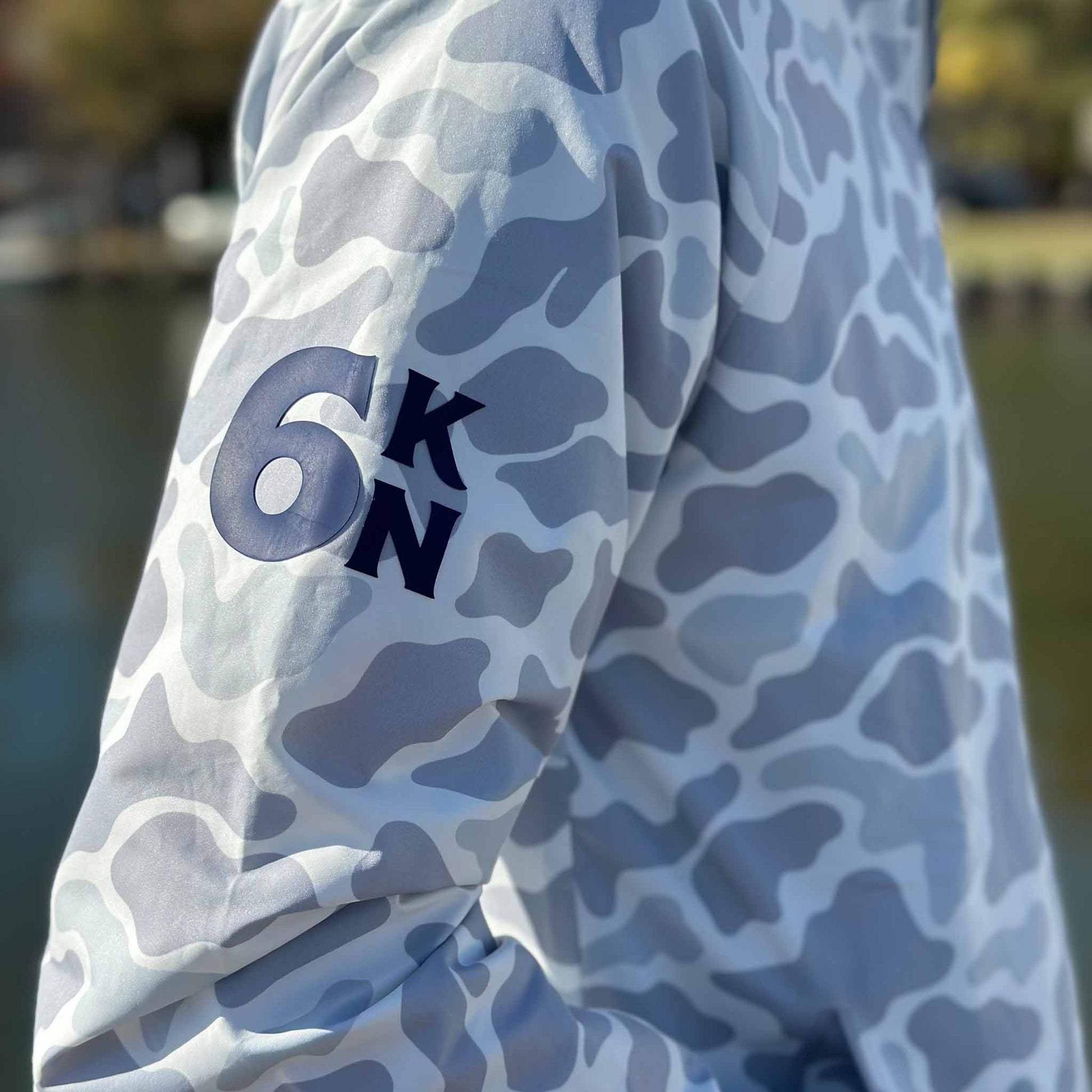 Close-up of Six Knots Coastal Camo Rain Jacket sleeve featuring the 6KN emblem — waterproof, lightweight outerwear for boaters and anglers