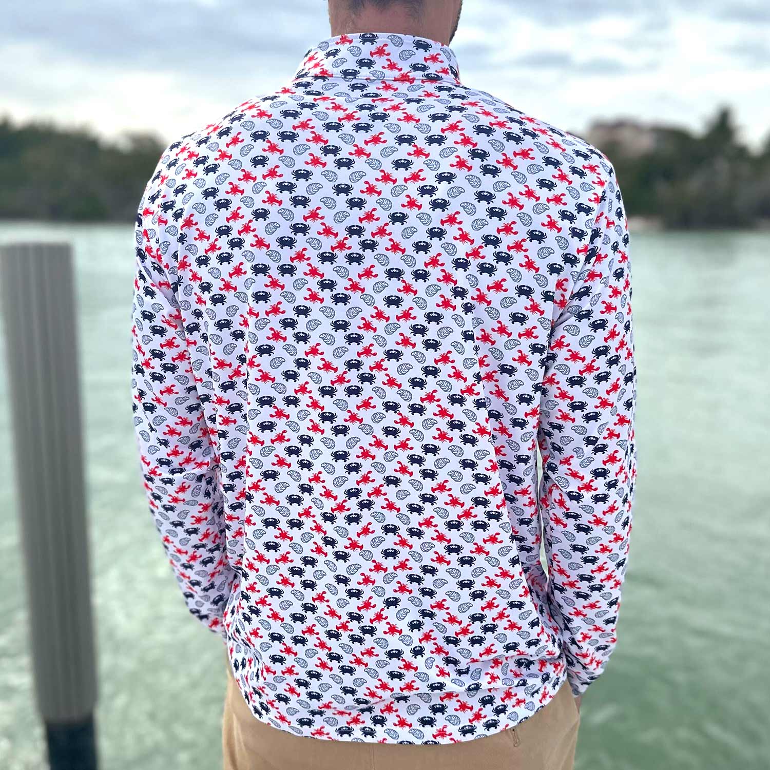 Rear view of man on a boat dock in Florida wearing the Six Knots East Coaster Performance Quarter Zip — breathable, quick-dry pullover with a red, white, and blue seafood pattern featuring lobsters, crabs, and oysters; perfect for fishing trips, boating outings, and all-day comfort during coastal adventures