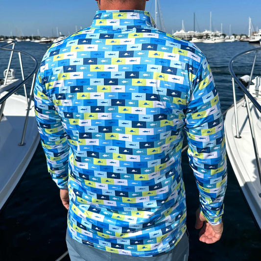 Rear view of man in a marina surrounded by powerboats wearing the Six Knots Fish Flag Men’s Performance Quarter Zip — lightweight, breathable, and moisture-wicking men’s fishing pullover featuring a bold all-over print of sportfish framed in nautical flag-style boxes of lime green, navy, light blue, and white; designed for saltwater fishing, offshore boating, and rugged coastal adventures in any weather.