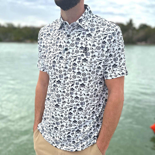 Man standing on a dock in Florida wearing the Six Knots Pirate's Life Performance Polo Shirt. This lightweight, moisture-wicking men's polo features an all-over black and white nautical pirate print with treasure chests, skull and crossbones, cannons, hooks, and maritime icons — perfect for boating, golfing, beach days, and coastal adventures