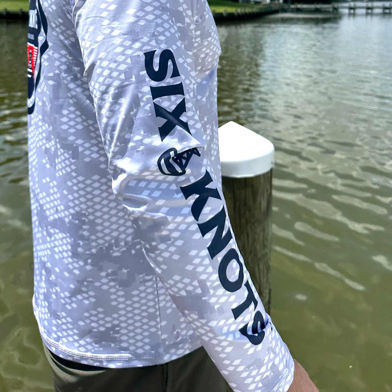 Close-up of the sleeve detail on the Six Knots Red Sky At Night Men’s Performance Crew in fish scale camo, featuring the bold, full-length Six Knots wordmark — lightweight, breathable, and moisture-wicking men’s fishing shirt with a digital gray camouflage pattern inspired by fish scales; engineered with UPF sun protection and quick-dry performance for saltwater fishing, offshore boating, and all-weather coastal adventures.