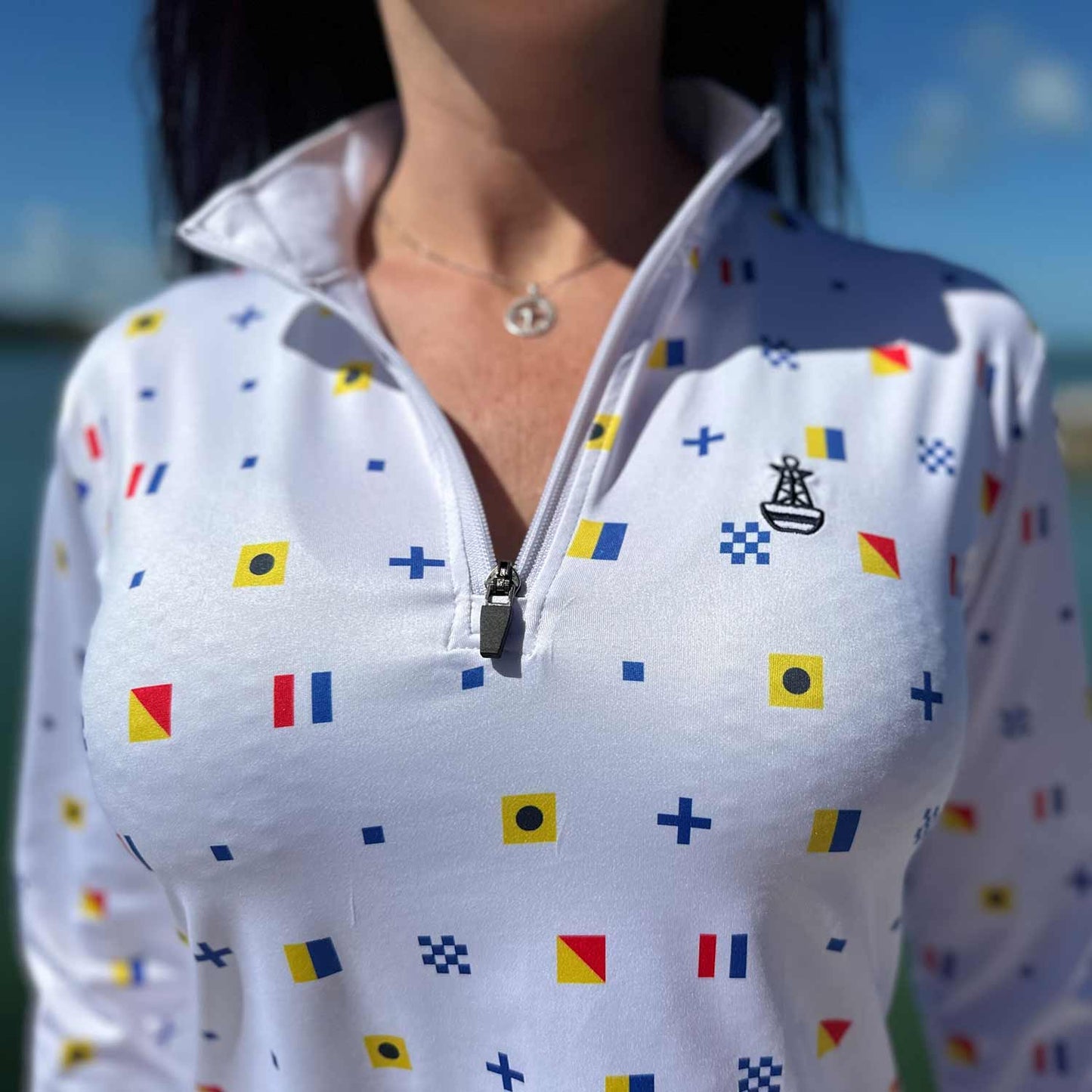 Close-up of the white Six Knots Signal Flag Women's Performance Quarter Zip highlighting the intricate repeating nautical signal flag pattern spelling "Six Knots" — lightweight, breathable, moisture-wicking pullover with UPF sun protection and all-weather comfort, ideal for fishing, boating, sailing, and coastal outdoor adventures