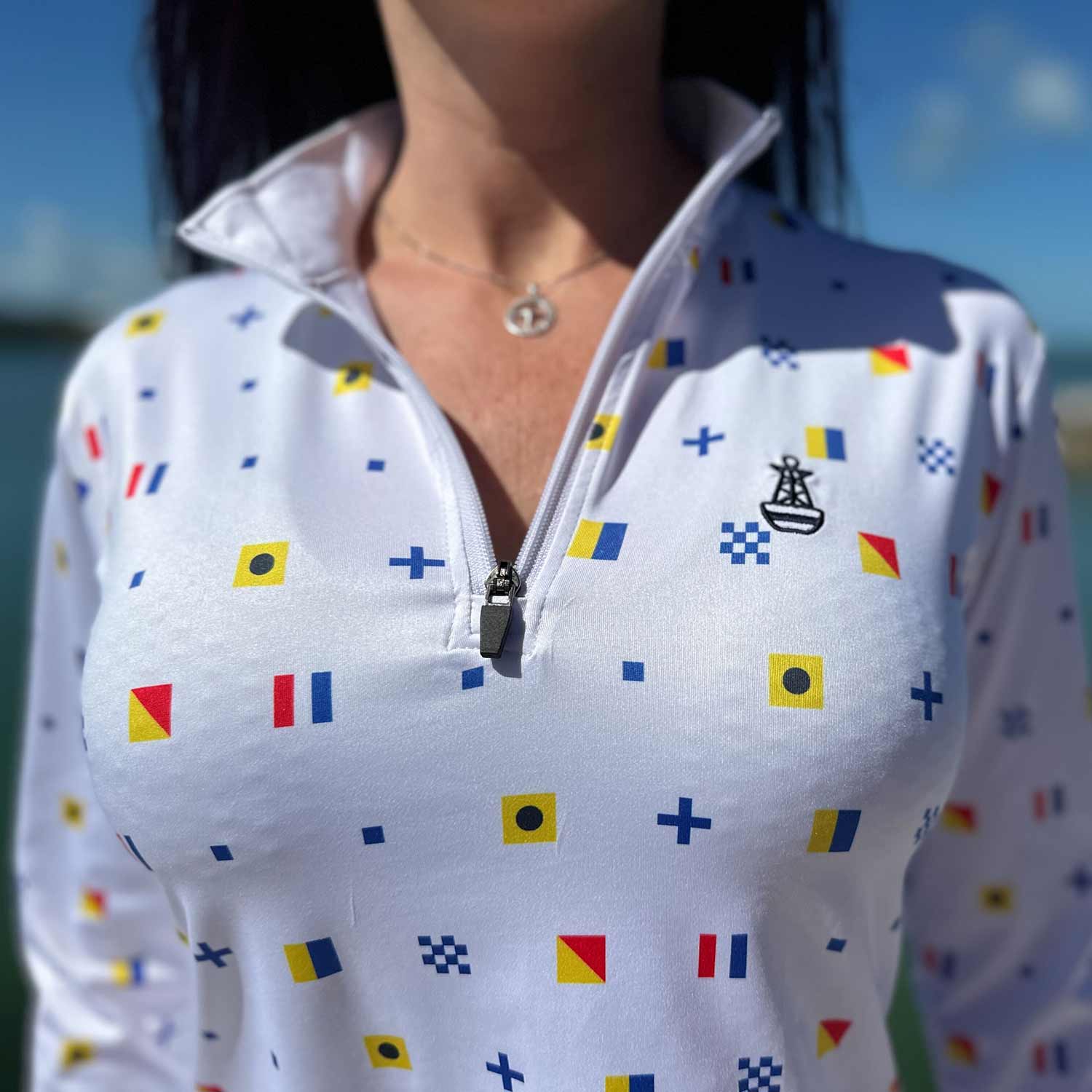 Close-up of the white Six Knots Signal Flag Women's Performance Quarter Zip highlighting the intricate repeating nautical signal flag pattern spelling "Six Knots" — lightweight, breathable, moisture-wicking pullover with UPF sun protection and all-weather comfort, ideal for fishing, boating, sailing, and coastal outdoor adventures