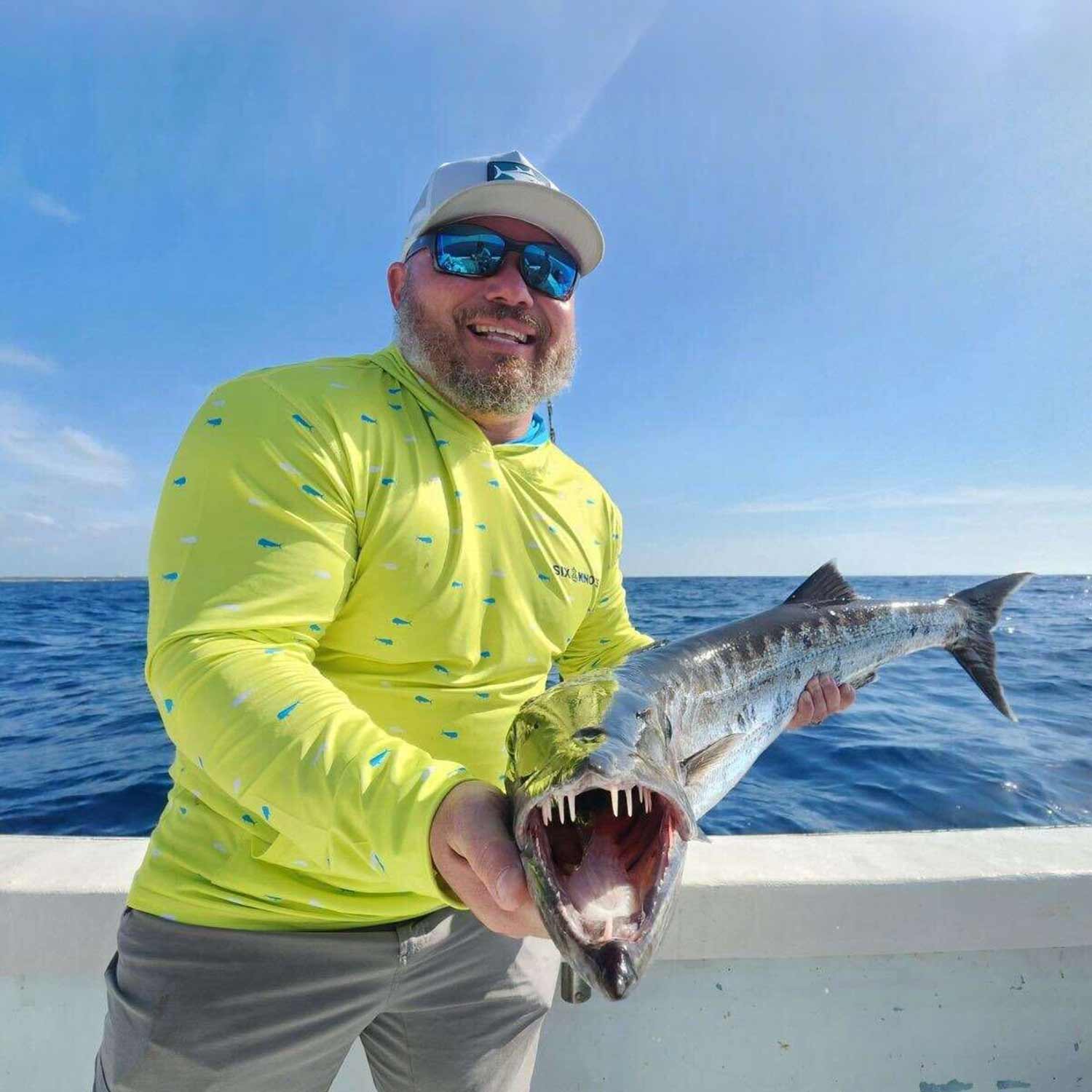 Man wearing a hoodie and hat holding a fish he just caught