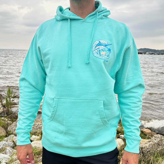 Man standing by the water wearing the Six Knots Summer Catch Classic Hoodie in vibrant turquoise — ultra-soft unisex hoodie crafted from a premium cotton-blend fabric for breathable, all-day comfort. Ideal for cool coastal mornings, casual seaside outings, and effortless layering during oceanfront adventures.