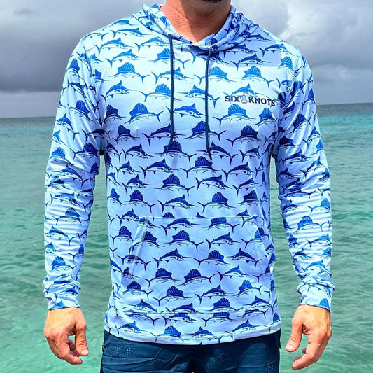 Front view of man in St. Maarten wearing the Six Knots Swords and Sails Performance Hoodie — lightweight, breathable fishing shirt with moisture-wicking fabric and all-over nautical print featuring swordfish and marlins, ideal for offshore fishing, boating, and tropical adventures