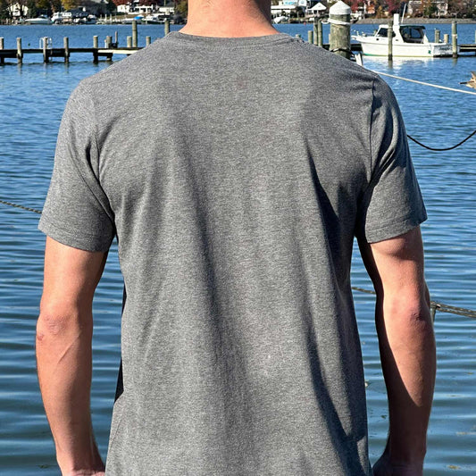 Rear view of man at a Maryland marina wearing the dark gray Six Knots Tropical Storm Classic T-Shirt. This ultra-soft, lightweight unisex tee is crafted from a breathable cotton-polyester blend. Ideal for everyday wear, weekend lounging, beach vacations, casual coastal outings, and relaxed waterfront style.