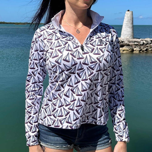 Woman standing on a marina dock wearing the Six Knots Under Sail Women's Performance Quarter Zip featuring a repeating hand-sketched sailboat pattern — lightweight, moisture-wicking, and breathable pullover with UPF sun protection and all-weather comfort, perfect for fishing, boating, sailing, and coastal lifestyle adventures