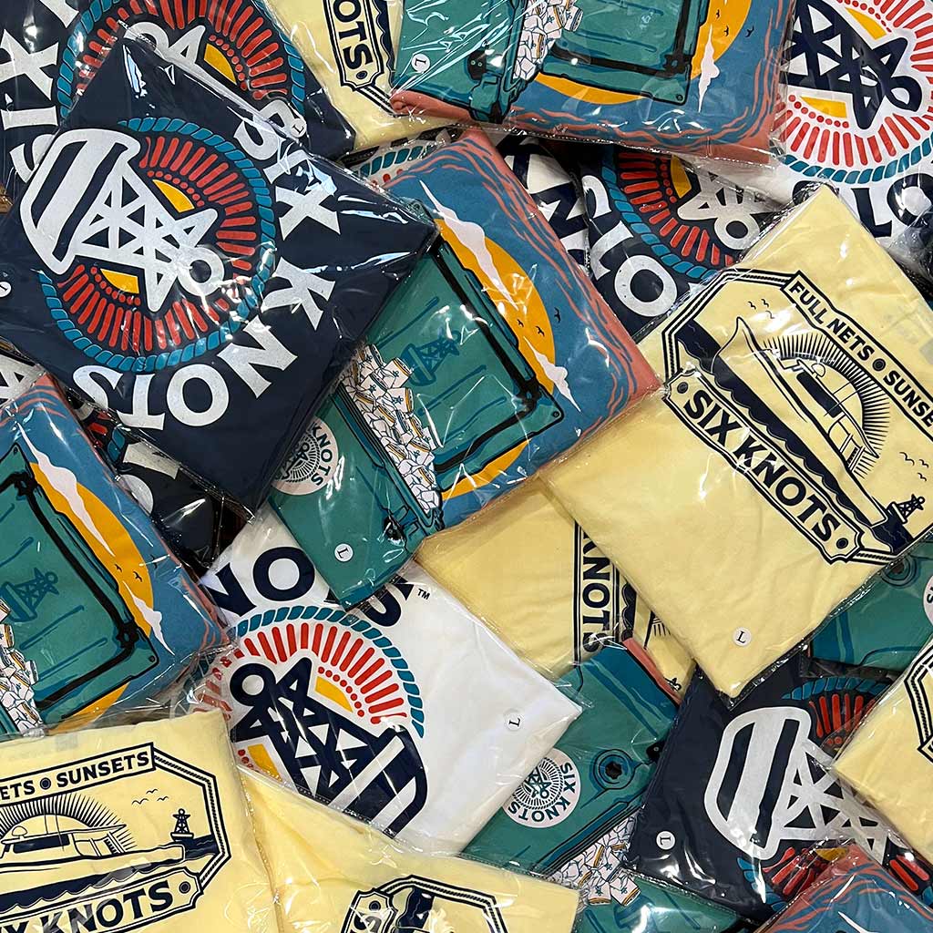 Six Knots shirts in a variety of colors in a pile