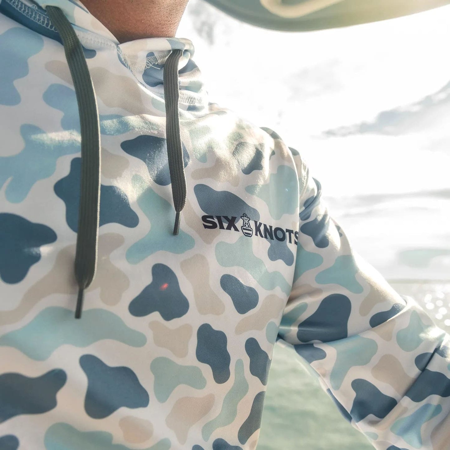 Close-up of man on a boat in Fort Lauderdale, Florida, wearing the Six Knots Coastal Camo Performance Hoodie – Marsh Pattern, a lightweight, moisture-wicking fishing hoodie with drawstrings designed for warm-weather boating and coastal conditions