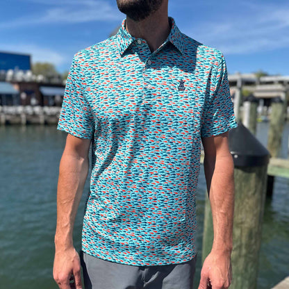 Man standing on a marina dock wearing the Six Knots Schoolie Performance Polo Shirt with vibrant fish pattern — breathable, quick-dry polo perfect for boating, fishing, and golf