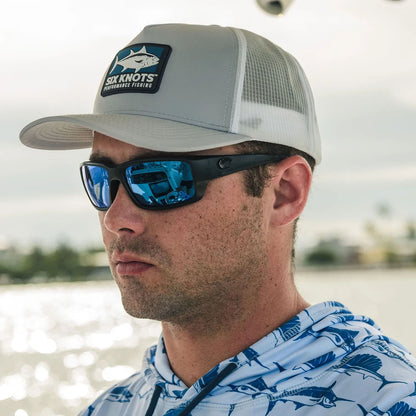 Man on a boat in Fort Lauderdale, Florida, wearing sunglasses and the Six Knots water-resistant Tuna Chaser Snapback Hat — designed for fishing and coastal adventures